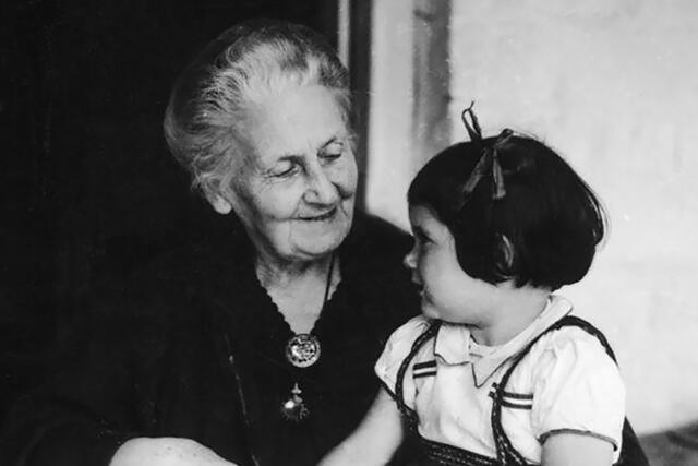 Maria Montessori and young child looking at each other